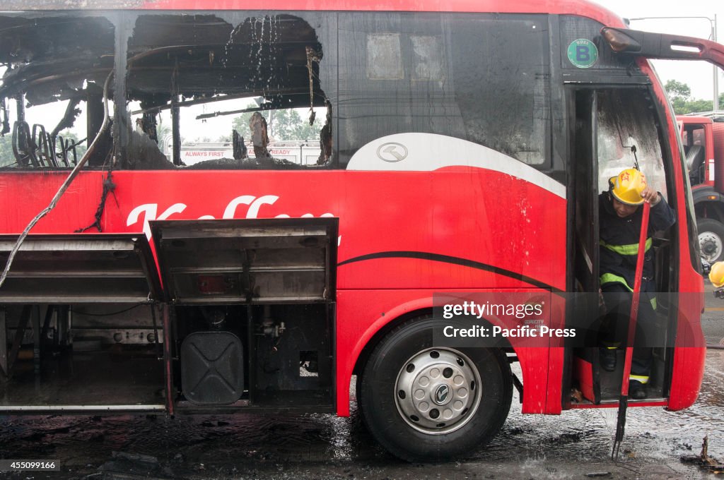 A fire-fighter steps out of the burned passenger bus along...