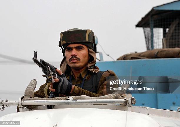 Paramilitary soldier stand guard on the top of his vehicle at the site of shootout at Nowgam bypass on December 11, 2013 on the outskirts of...