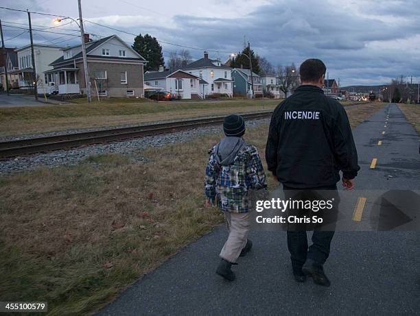 Sylvain Gregoire walks along the deadly down hill sloping track towards town with his 7-year-old son Cedrick in Lac-Megantic. Gregoire is an...