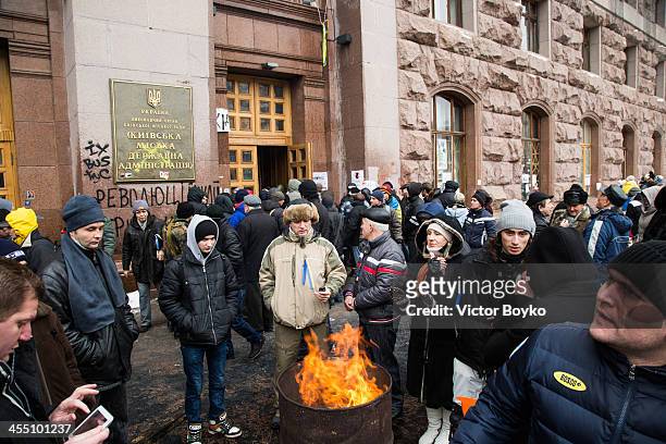 Protesters warm themselves near a fire outside the City Hall entrance after the riot police were forced out from blocking the front door, as...