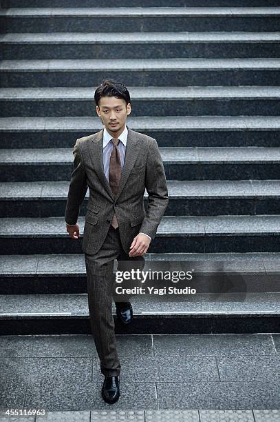 young businessman is down the stairs - bruin pak stockfoto's en -beelden