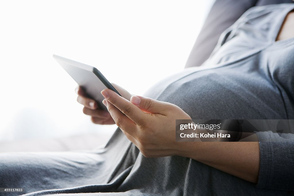 A pregnant woman using a digital tablet