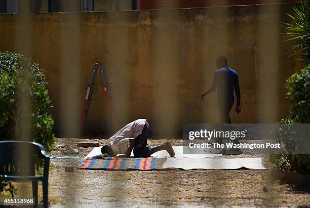 An African migrant man is seen praying in the yard at the former Aloha B&B Palace where migrants now reside on August 24, 2014 in Portopalo di Capo...