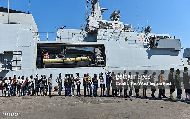 African migrant men wait in line to have medical evaluations after disembarking from the Italian Navy ship Foscari on August 23, 2014 in Portopalo di...
