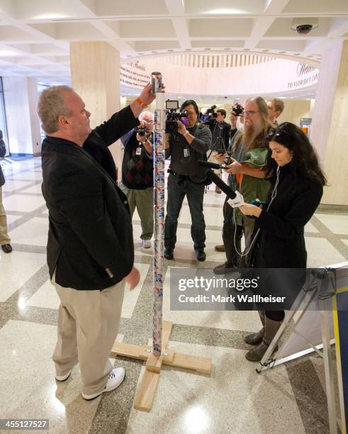 Chaz Stevens from Deerfield Beach, Florida assembles his Festivus pole out of beer cans in the rotunda of the Florida Capitol as the media looks on...