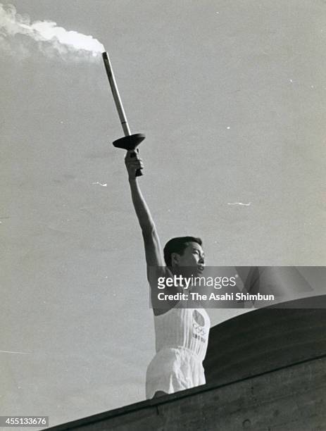 Tokyo Olympic final torch runner Yoshinori Sakai lights the Olympic cauldron during the opening ceremony of the 1964 Tokyo Olympics at the national...