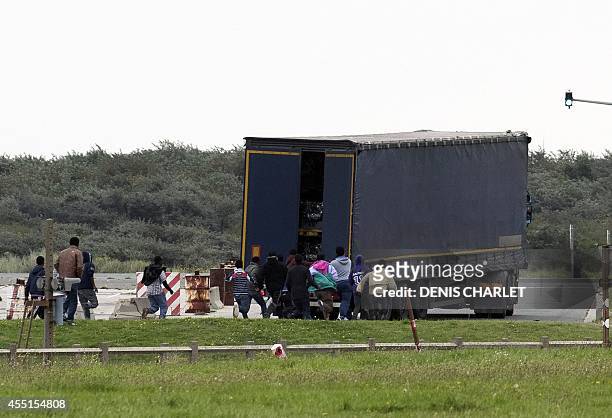 Illegal migrants run toward a truck about to board a ferry to Great Britain, on September 10, 2014 in the French port of Calais. Illegal camps of...