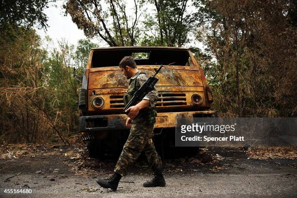 Separatist fighter stands beside a Ukrainian military truck which was destroyed during recent fighting on September 10, 2014 in Alovaisk, Ukraine....