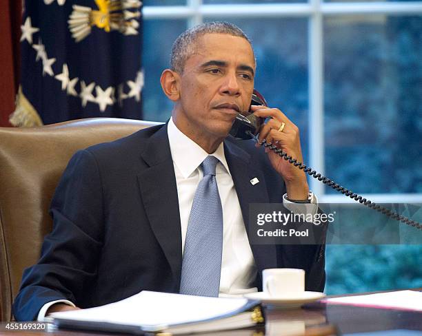 President Barack Obama, seen through an Oval Office window, speaks on the phone with King Abdallah Abd al Aziz of the Kingdom of Saudi Arabia at the...