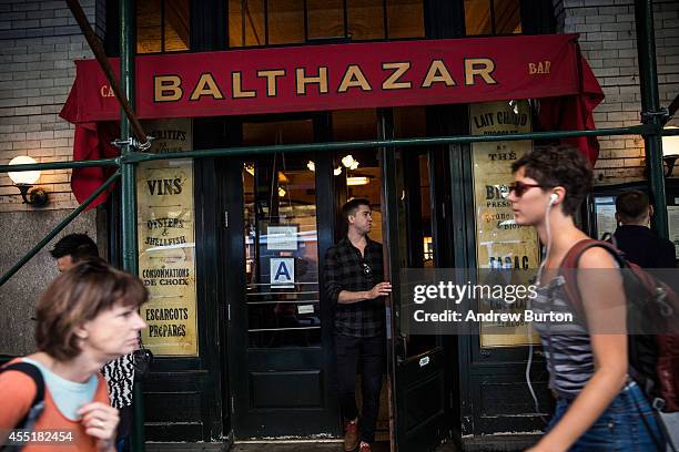 People walk past the restaurant Balthazar, near the construction site at 42 Crosby Street, which is being developed into a luxury apartment building...