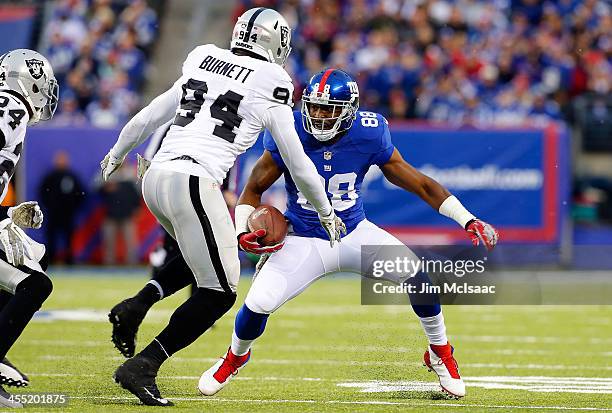 Hakeem Nicks of the New York Giants runs the ball against Kevin Burnett of the Oakland Raiders on November 10, 2013 at MetLife Stadium in East...