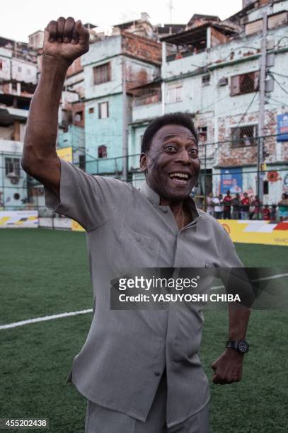 Legendary Brazilian former football player Pele raises his fist during the inauguration ceremony of the new technology football pitch installed at...