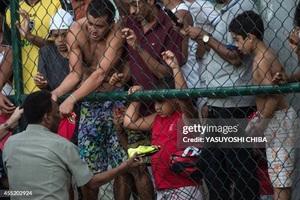 Legendary Brazilian former football player Pele gives a signed boot to a child during the inauguration ceremony of the new technology football pitch...