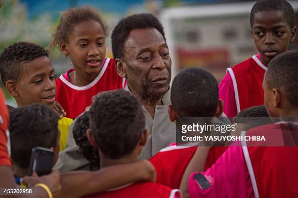Legendary Brazilian former football player Pele speaks with children during the inauguration ceremony of the new technology football pitch installed...