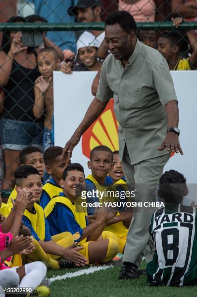 Legendary Brazilian former football player Pele greets children during the inauguration ceremony of the new technology football pitch installed at...