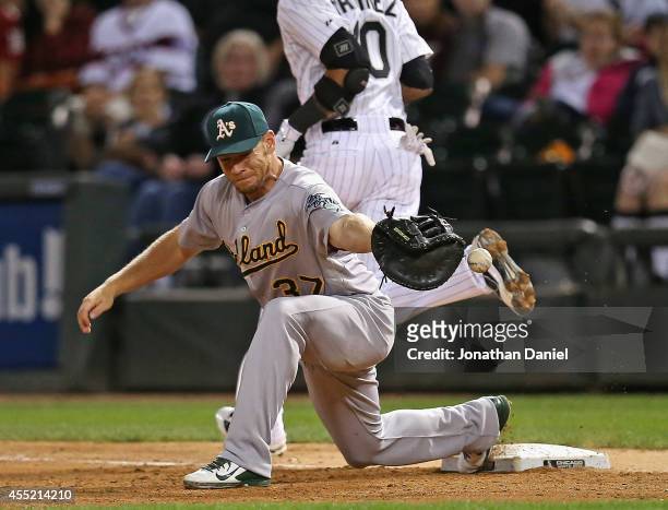 Brandon Moss of the Oakland Athletics can't handle a throw to get Alexei Ramirez of the Chicago White Sox at first base in the 6th inning at U.S....
