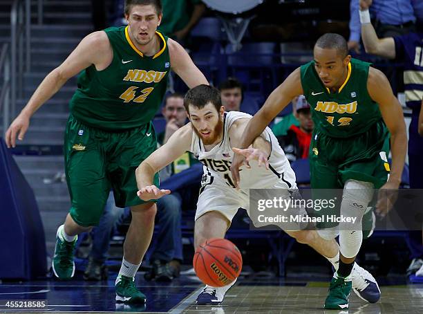 Garrick Sherman of the Notre Dame Fighting Irish reaches for the loose ball in front of Marshall Bjorklund and Lawrence Alexander of the North Dakota...