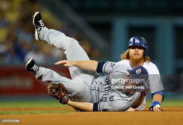 Second baseman Jedd Gyorko of the San Diego Padres falls over Justin Turner of the Los Angeles Dodgers after forcing him out a second base, as part...