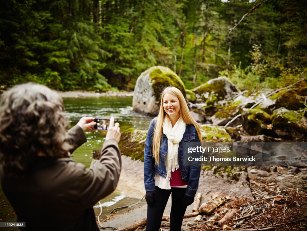 Woman taking photo of friend with smartphone