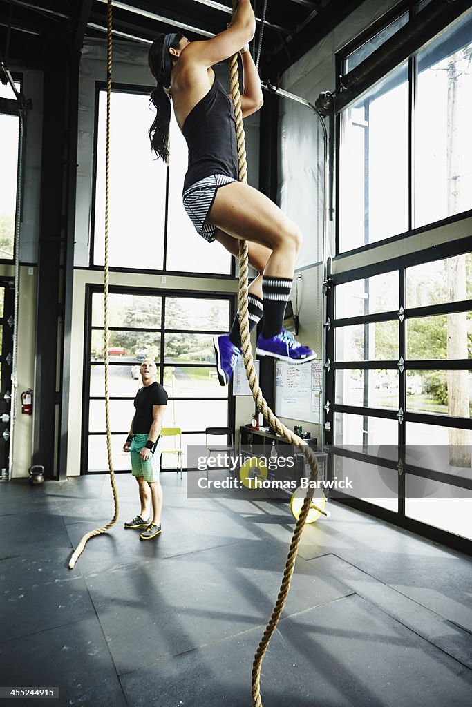 Woman climbing rope in gym gym