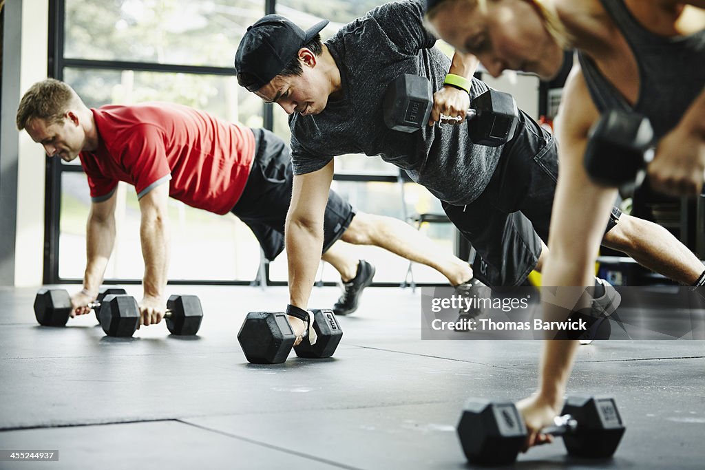 Group of friends doing pushups with dumbbells