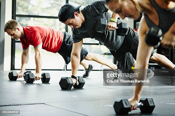 group of friends doing pushups with dumbbells - ginnastica foto e immagini stock