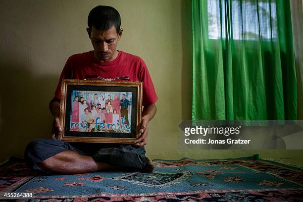 Café owner Amirizal points to a photograph of his family before the tsunami which took nine of his eleven brothers and leaving him with only one leg....