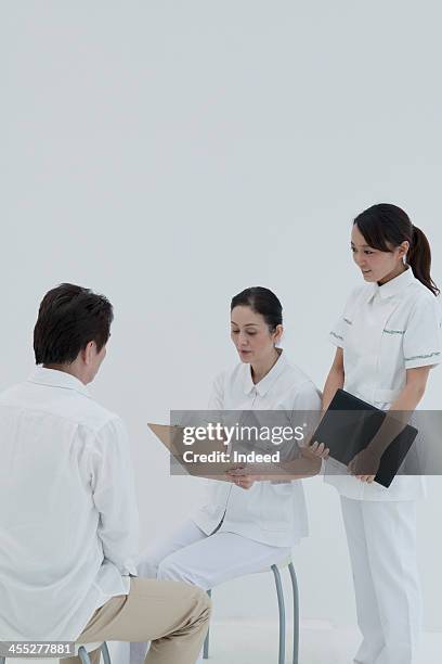middle-aged nurse and young nurse who asks man - nurse and portrait and white background and smiling and female and looking at camera stock pictures, royalty-free photos & images