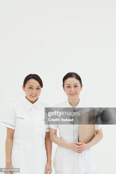 charge nurse and young nurse - nurse and portrait and white background and smiling and female and looking at camera stock pictures, royalty-free photos & images