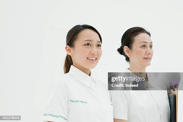 charge nurse and young nurse - nurse and portrait and white background and smiling and female and looking at camera stock pictures, royalty-free photos & images