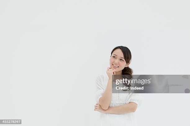 the smiling face of young woman - woman thinking hand on chin stock pictures, royalty-free photos & images