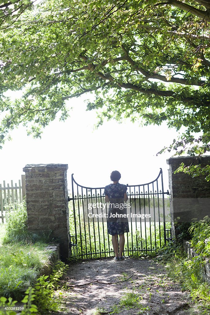 Woman standing in front of gate, rear view