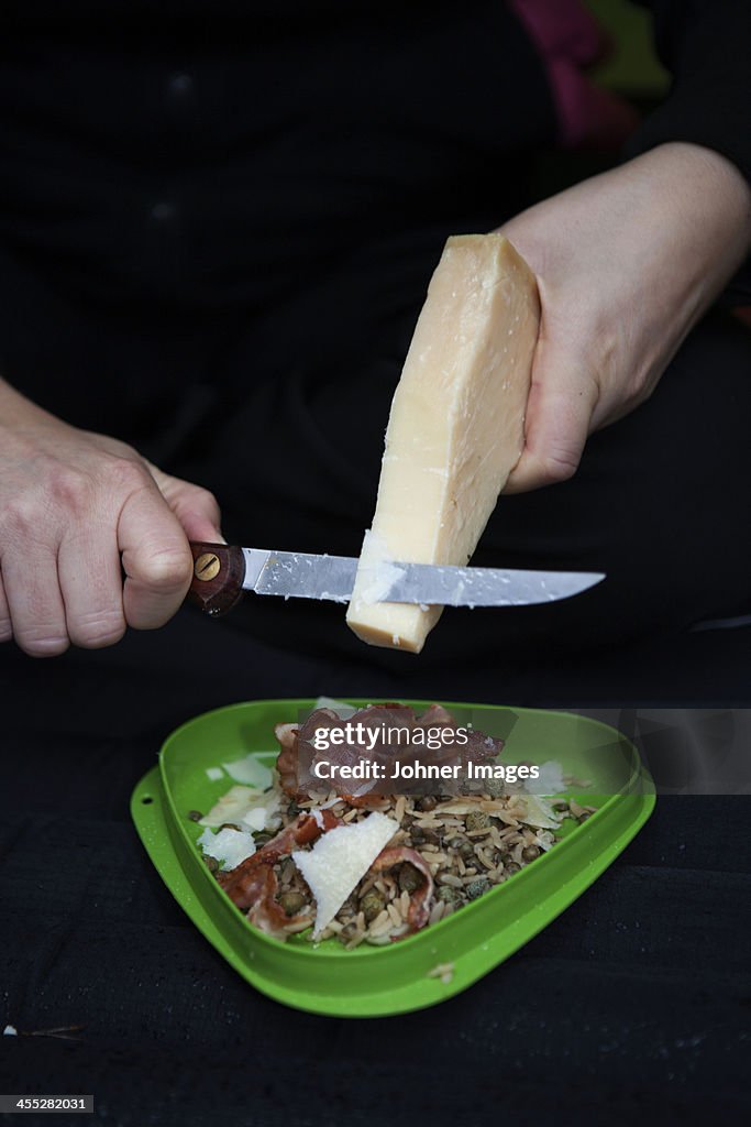 Woman cutting Parmesan cheese into salad