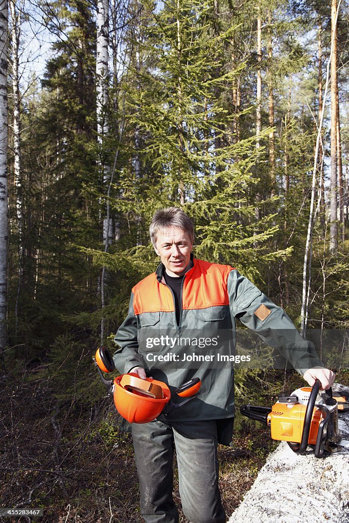 Portrait of man with chainsaw in forest