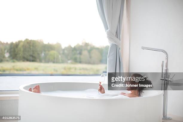 young woman having bath and drinking wine - bath spa stock-fotos und bilder