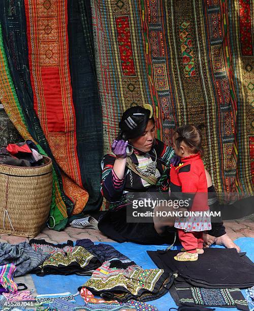 This picture taken on December 8, 2013 shows a Hmong ethnic woman selling souvenir items made of traditional materials along a street in downtown of...