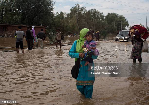Kashmiri Muslim woman carrying her child walks in a submerged highway in a flooded area on September 12, 2014 in Srinagar, the summer capital of...
