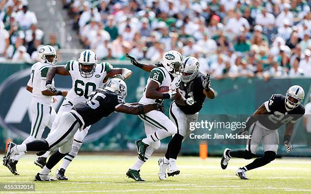 Chris Johnson of the New York Jets runs the ball against Justin Tuck, Sio Moore, and Charles Woodson of the Oakland Raiders on September 7, 2014 at...
