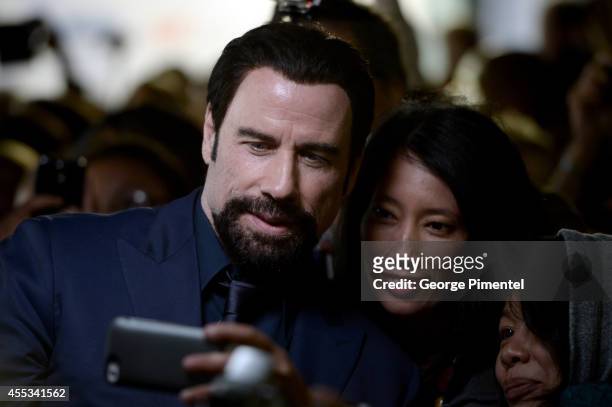 Actor John Travolta takes a selfie with fans as he attends "The Forger" premiere during the 2014 Toronto International Film Festival at Roy Thomson...