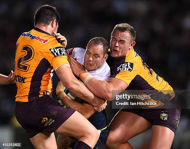 Matthew Scott of the Cowboys is tackled by Matt Gillett and Martin Kennedy of the Broncos during the NRL 1st Elimination Final match between the...