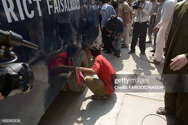 Pakistan Tehreek-e-Insaf worker deflates the tyre of a police prison van carrying arrested workers to prevent them from leaving the court area in...