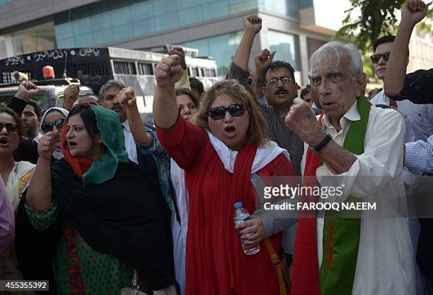 Activists of Pakistan Tehreek-e-Insaf shout slogans as they gather around a police prison van carrying arrested workers to prevent them from leaving...