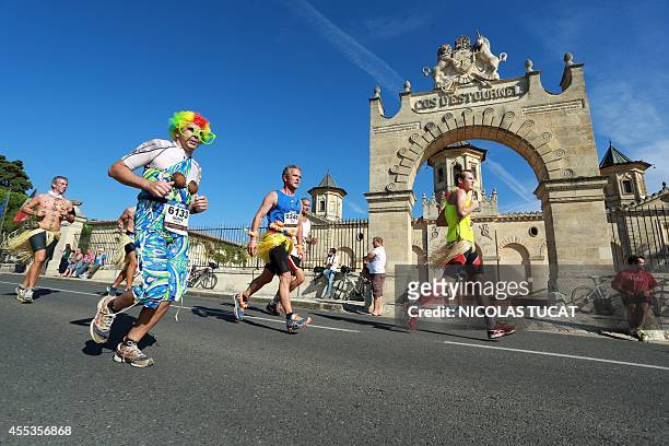 An Athlete dresses as a clown puns past Chateau Cos d'Estournel, near Pauillac, during the 30th Marathon du Medoc, a 26-mile circuit in the Medoc...