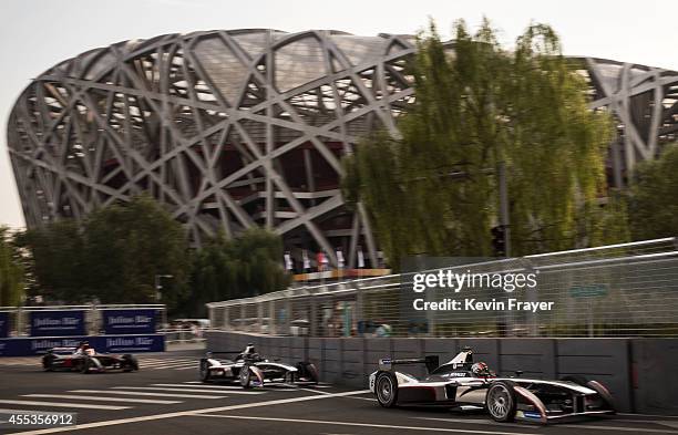 The two team cars of Dragon racing pass the Birds Nest Olympic Stadium during the FIA Formula E Beijing ePrix Championship on September 13, 2014 in...