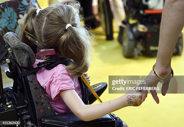 Disabled girl holds her mother's hand during a ceremony to launch the 28th Telethon, France's biggest annual fund-raising event, on September 13,...