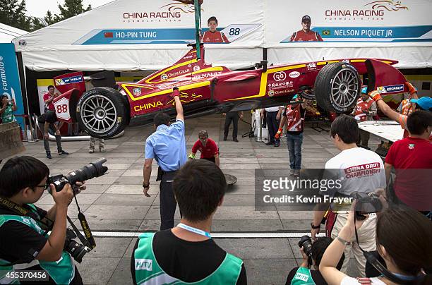 People gather around as a car from China Racing is brought back to the pits after driver Ho Ping Tung crashed it in practice before the inaugral FIA...