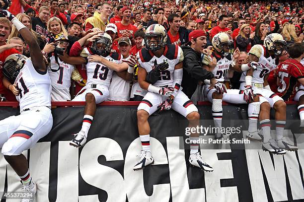 Defensive back Zach Dancel of the Maryland Terrapins and teammates jump into the crowd before playing the West Virginia Mountaineers during an NCAA...