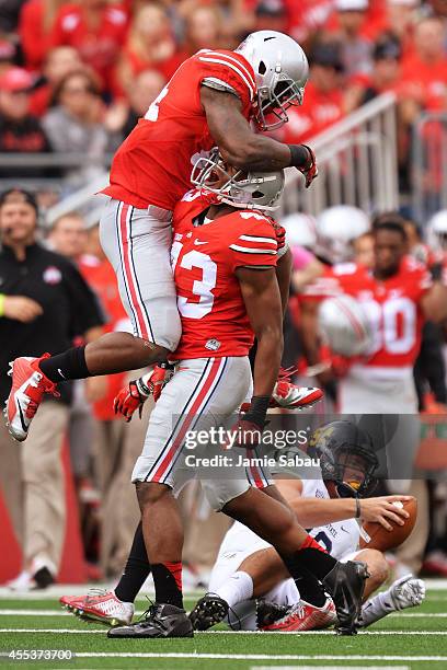 Curtis Grant of the Ohio State Buckeyes and Darron Lee of the Ohio State Buckeyes celebrate after Lee sacked quarterback Colin Reardon of the Kent...