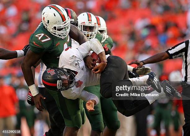 Fredi Knighten of the Arkansas State Red Wolves is sacked by Ufomba Kamalu of the Miami Hurricanes during a game at Sunlife Stadium on September 13,...