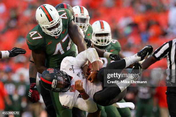 Fredi Knighten of the Arkansas State Red Wolves is sacked by Ufomba Kamalu of the Miami Hurricanes during a game at Sunlife Stadium on September 13,...